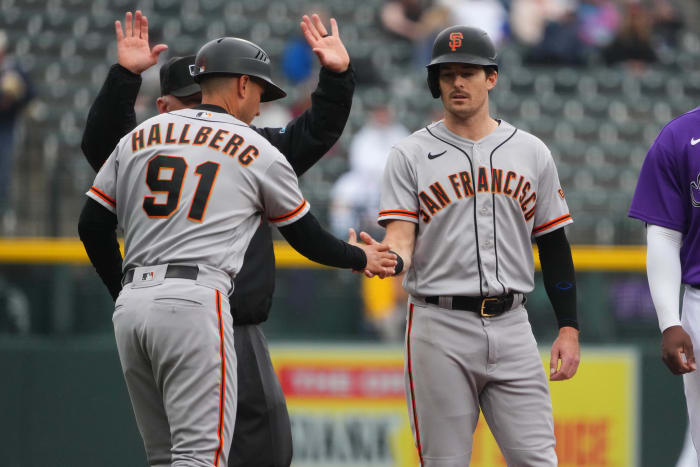 SF Giants outfielder Mike Yastrzemski high-fives third-base coach Mark Hallberg during their game against the Rockies on September 22, 2022.